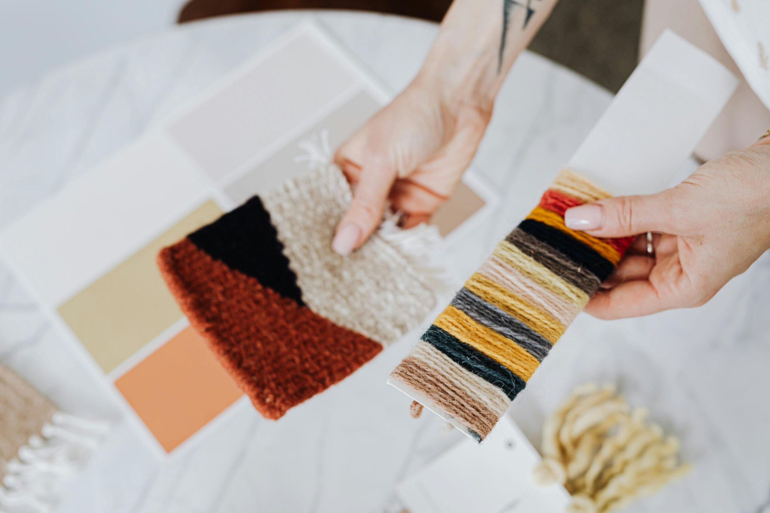 Hands holding fabric and thread samples for interior design inspiration.